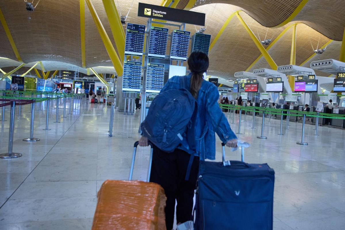 Una joven consulta el horario de los vuelos de salida en el aeropuerto de Madrid.
