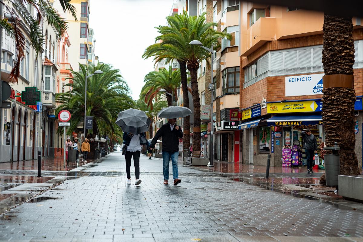 Dos personas con un paraguas, resguardándose de la lluvias en Las Palmas de Gran Canaria.