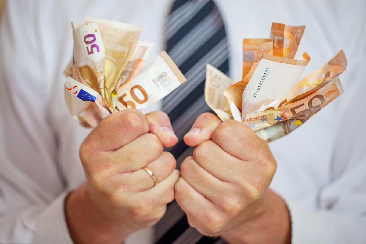 Un hombre agarrando billetes de 50 euros.