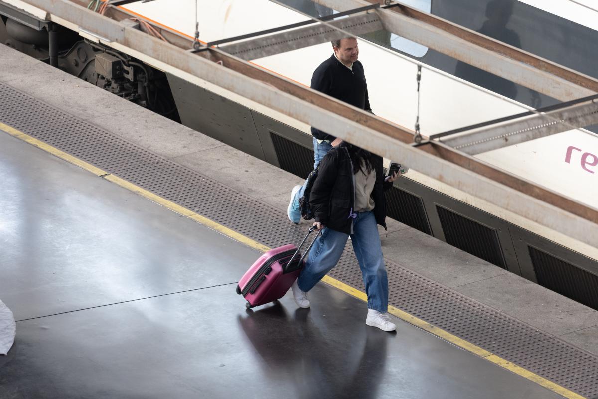 Una mujer paseando frente a un tren de Renfe.