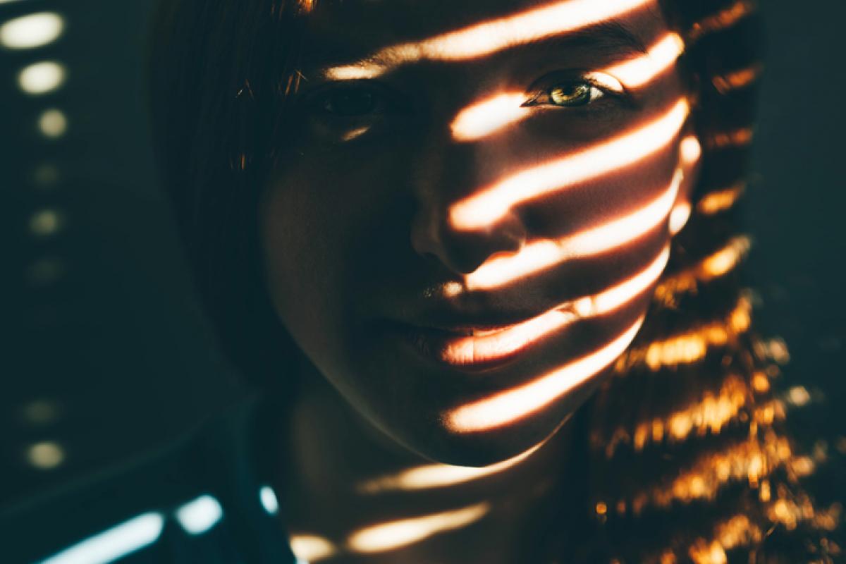 Imagen de archivo de una mujer con la sombra de las cortinas proyectada en su rostro.