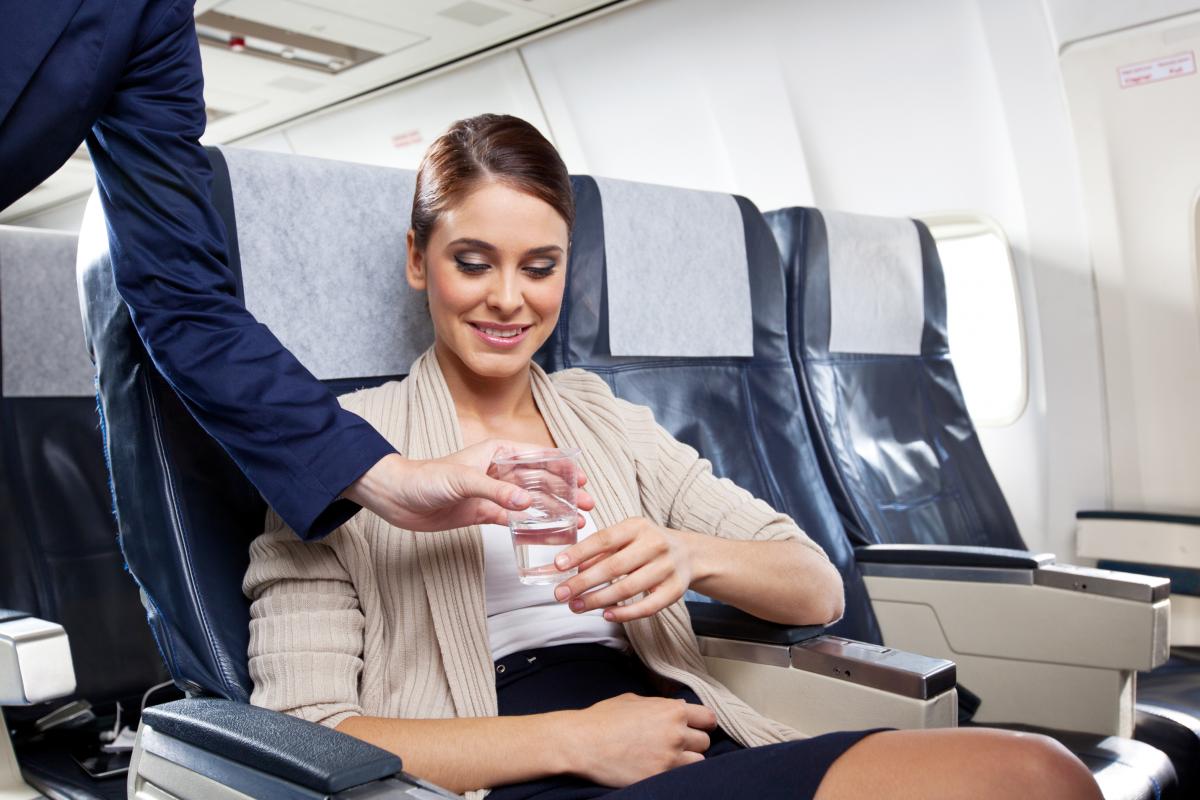 Una joven recibe un vaso de agua en un vuelo.