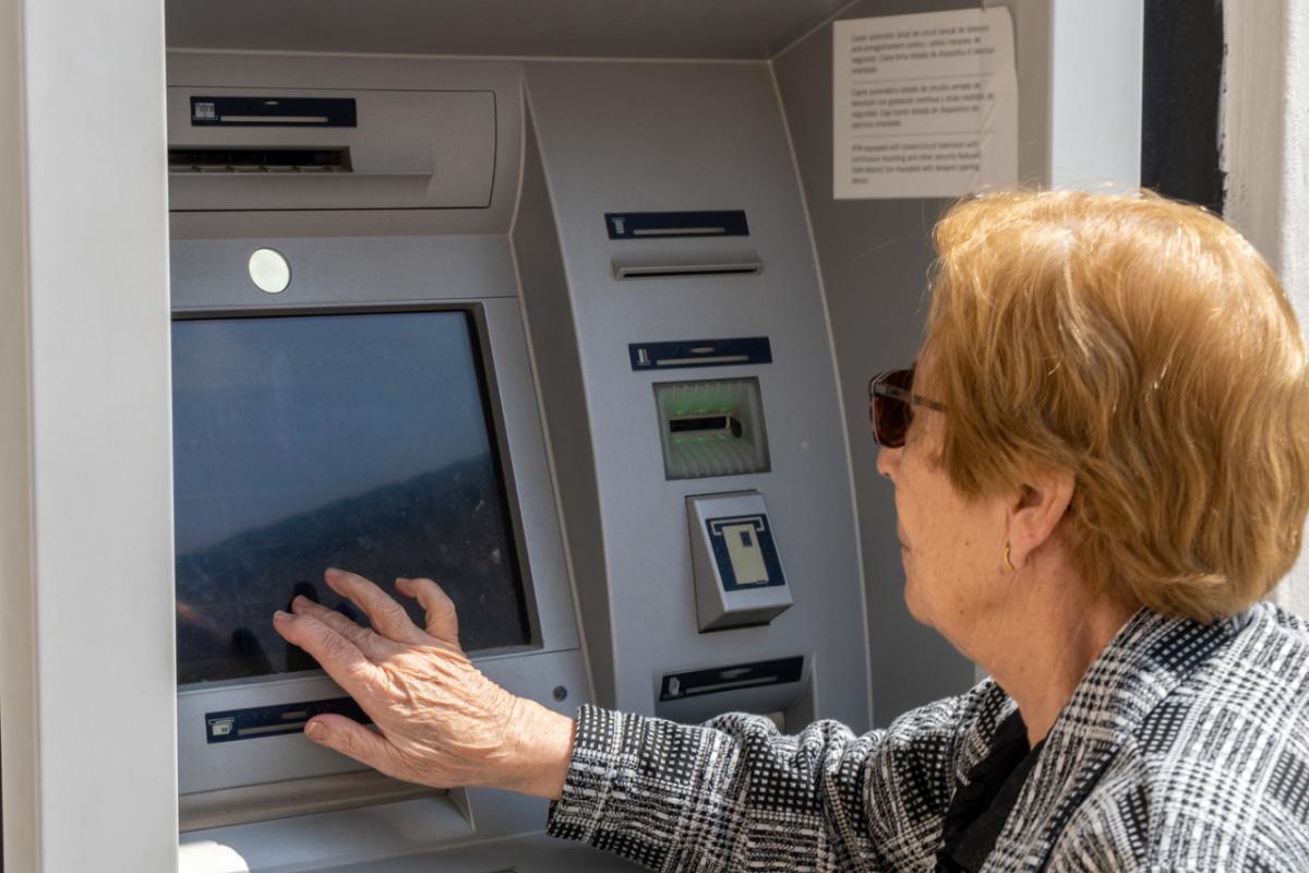 Una mujer de la tecera edad utilizando un cajero.