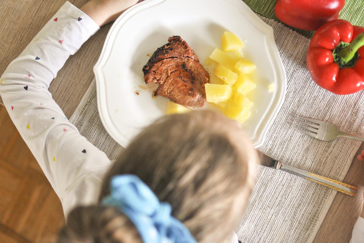 Imagen de archivo de una niña comiendo pescado.