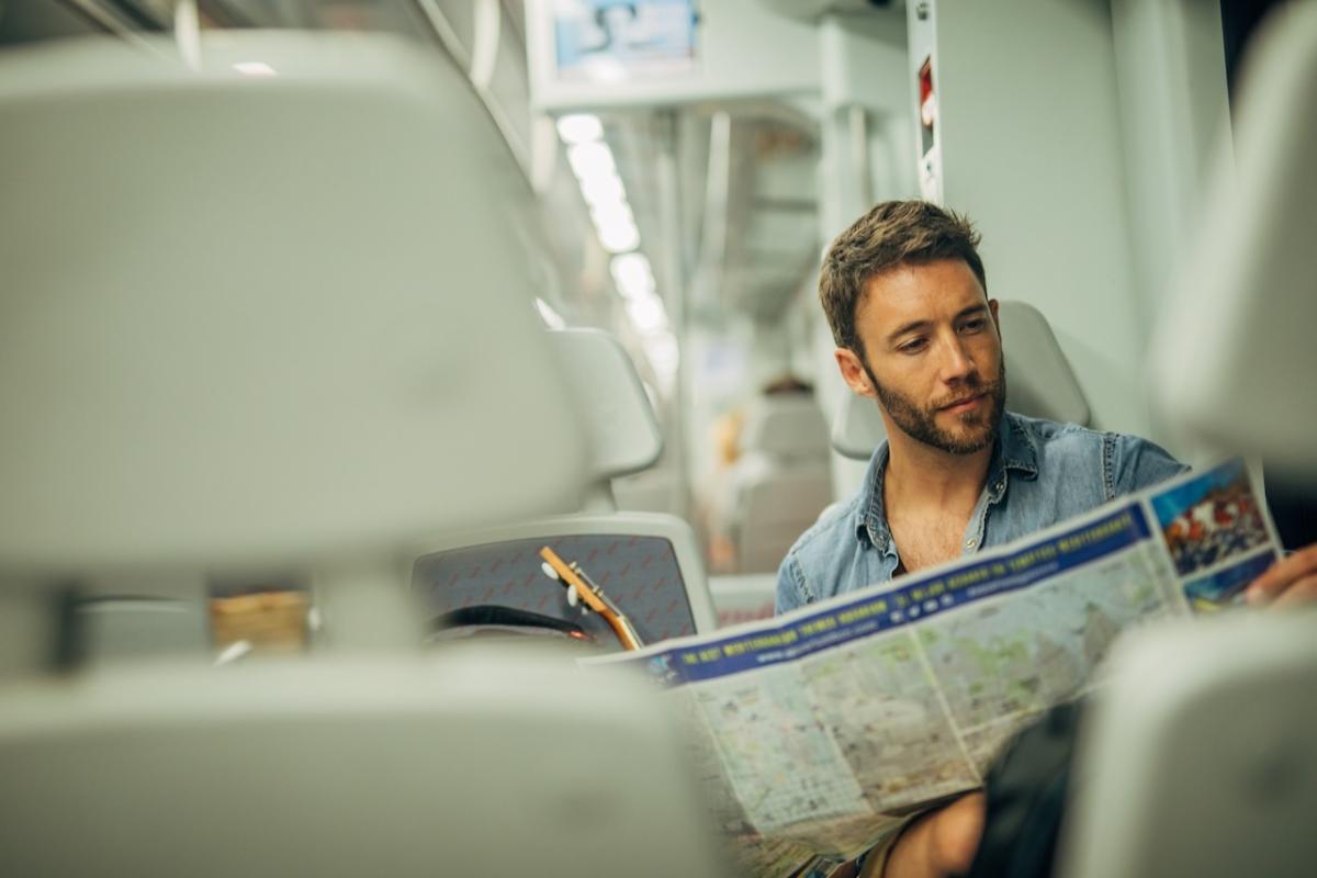 Un turista consulta un mapa de de España mientras viaja en tren.