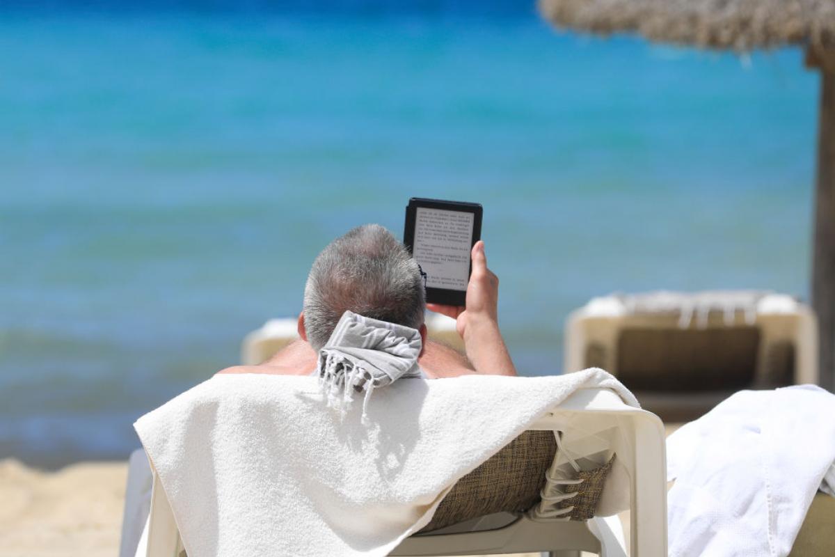 Un turista toma el sol mientras lee en una playa de Mallorca.