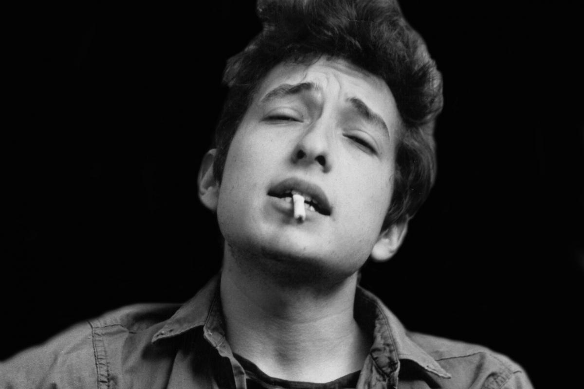 Bob Dylan tocando la guitarra y fumando en una foto sacada en 1962