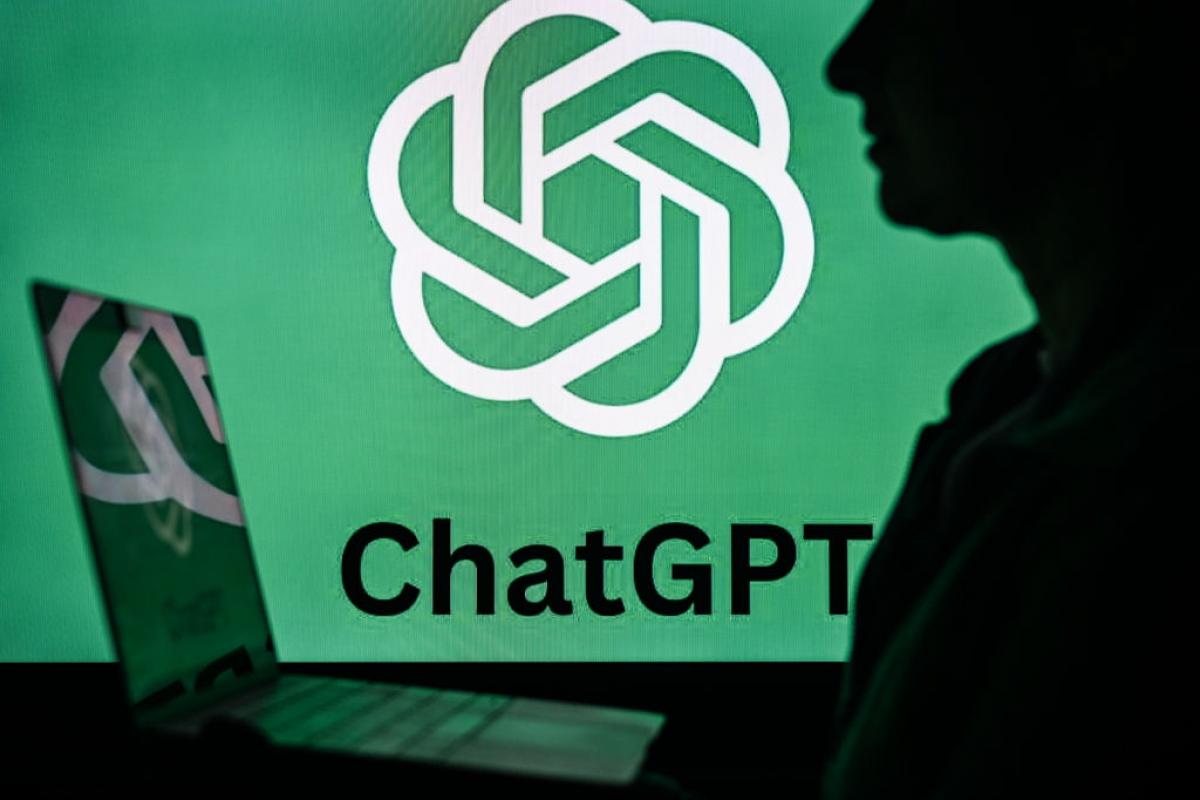 Una mujer sostiene un portátil delante de un logotipo de ChatGPT.