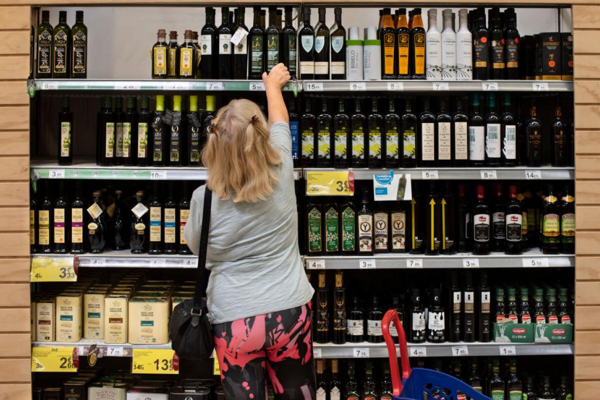 Una mujer coge una botella de aceite de oliva en un supermercado de Carrefour.