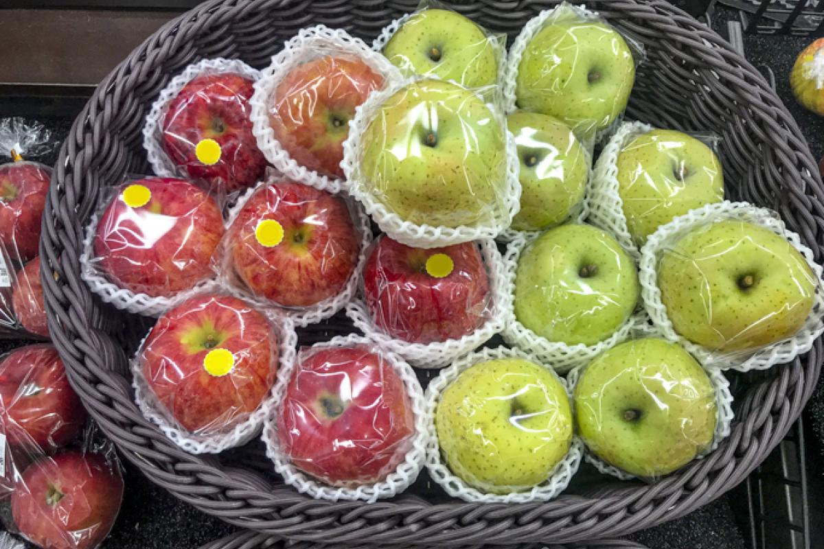 Imagen de archivo de manzanas envueltas en plástico.