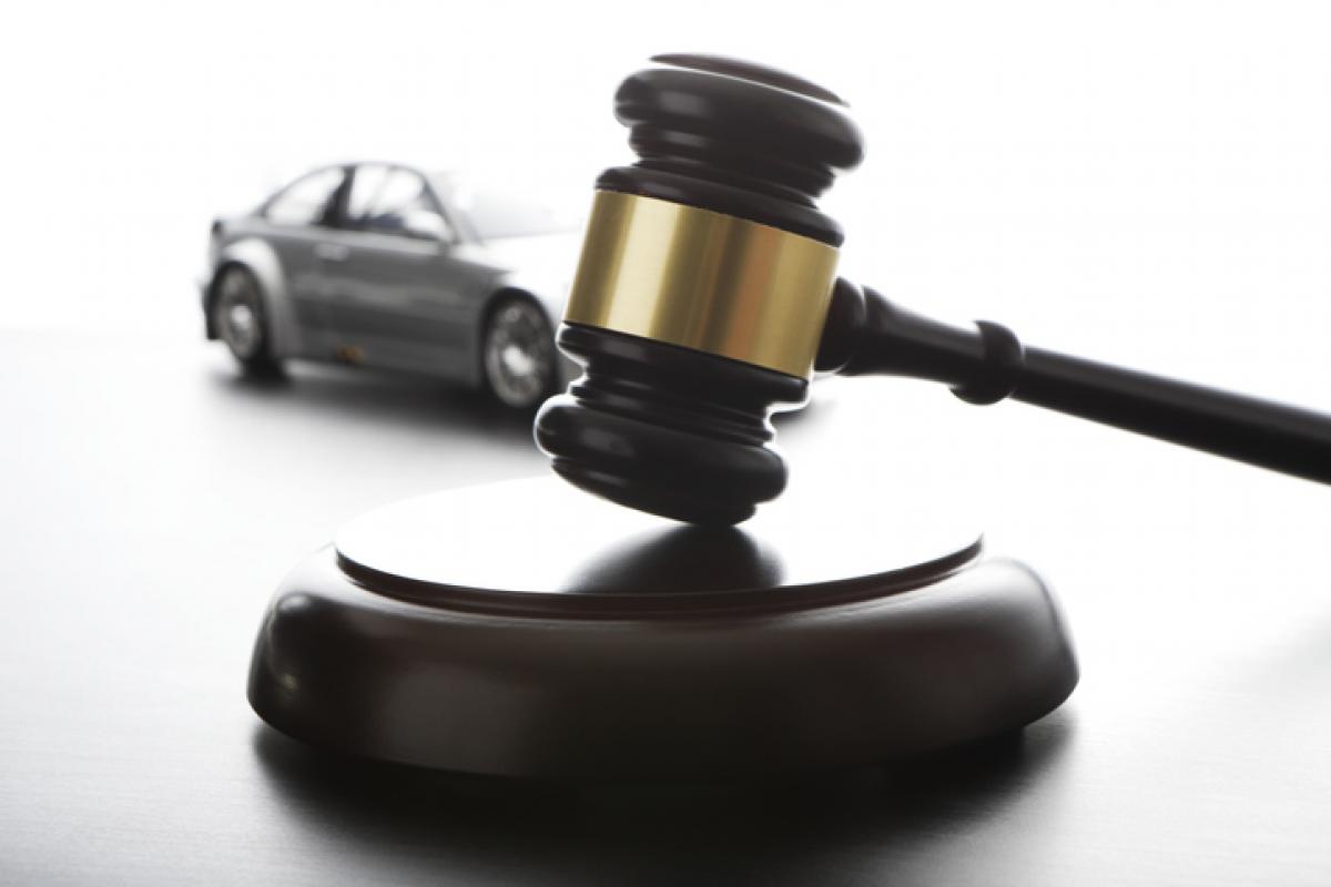 Imagen de un mazo de subastas con un coche al fondo.