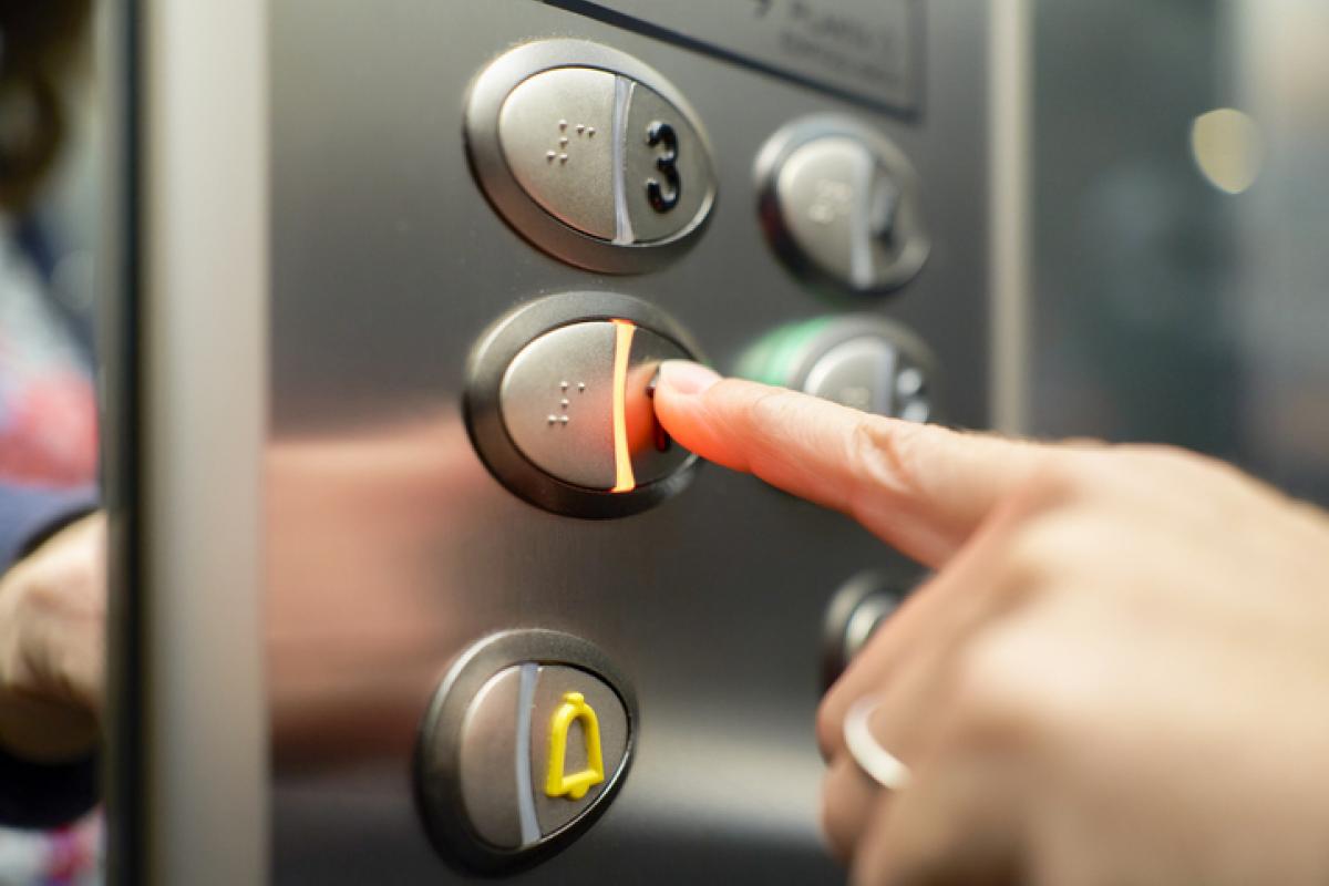 Imagen de archivo de una persona pulsando el botón de un ascensor.