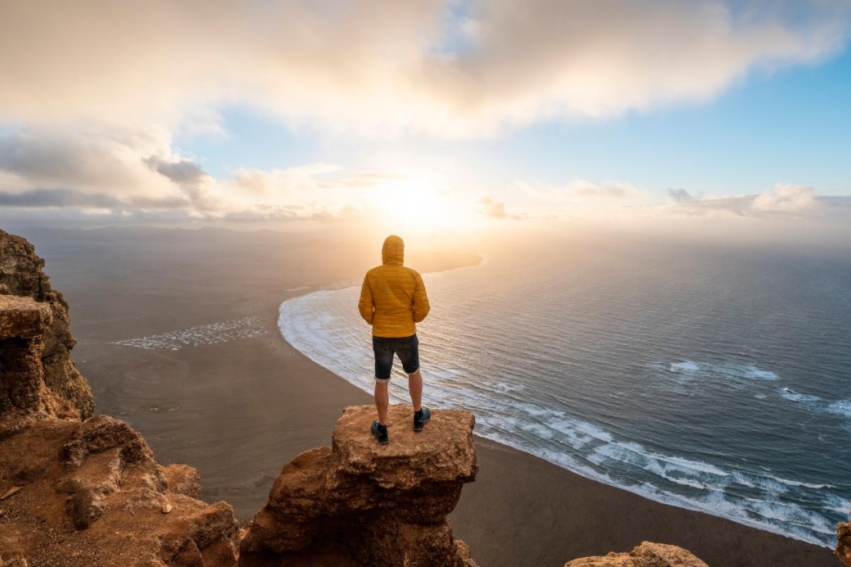 Persona admirando el atardecer en una playa de Lanzarote