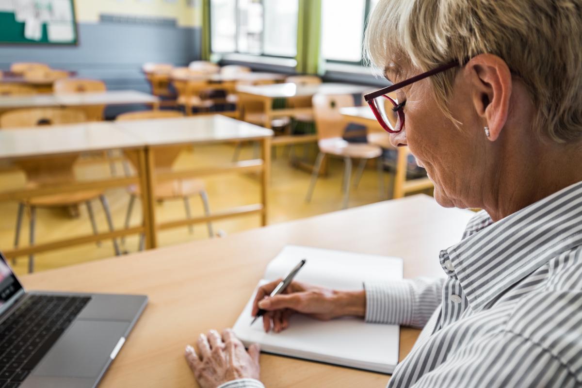 Una mujer mayor tomando notas en clase.