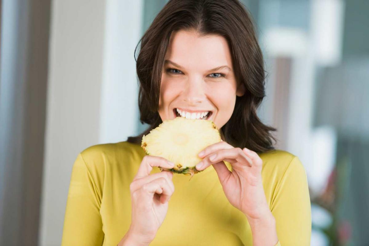 Mujer comiendo un trozo de piña con ganas
