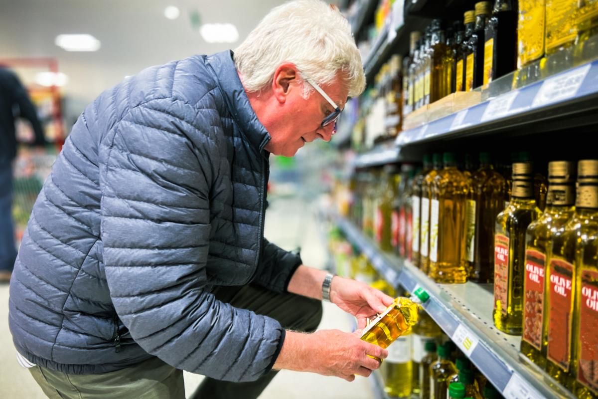 Un cliente mirando el precio del aceite de oliva en el supermercado.