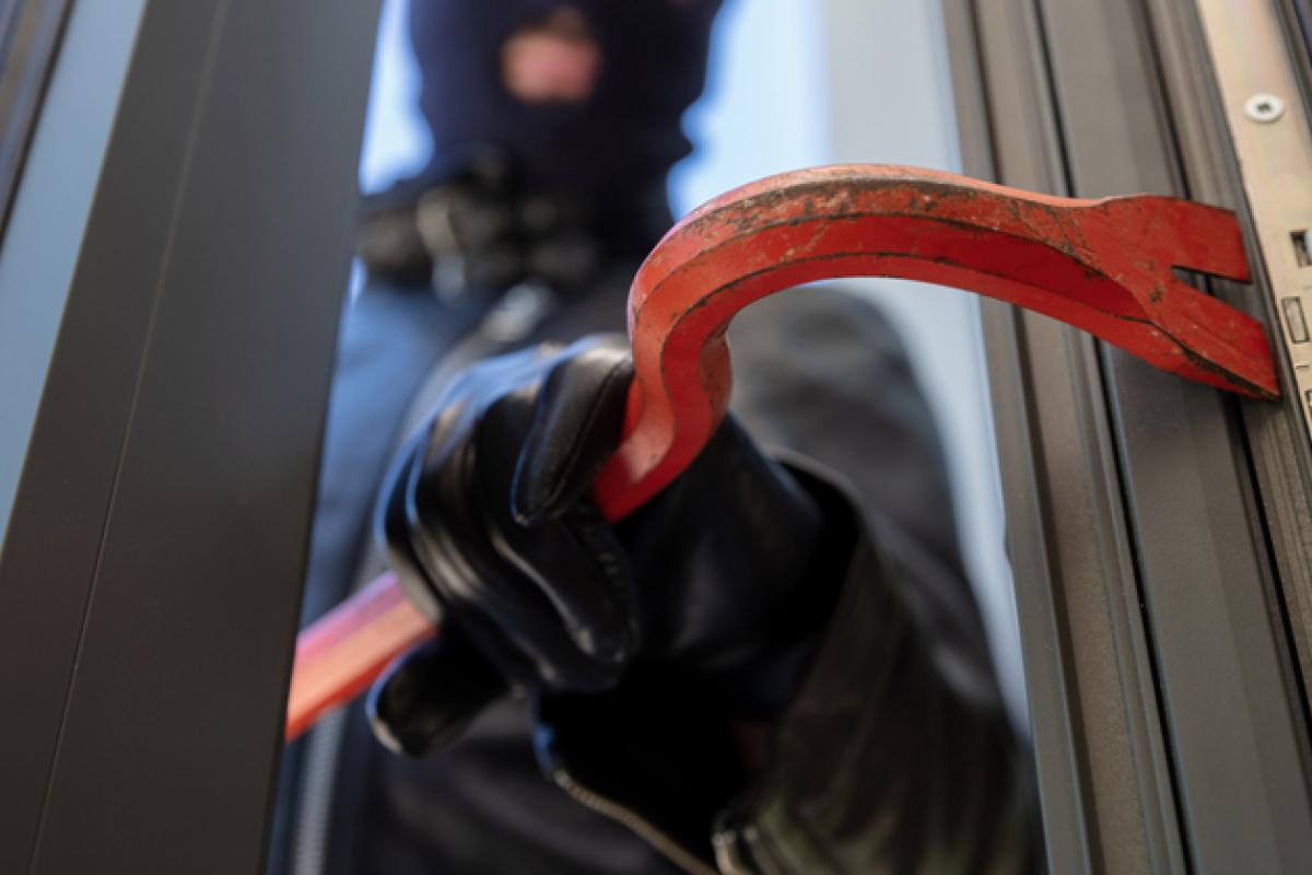 Imagen de un hombre forzando una puerta de un domicilio con una palanca.