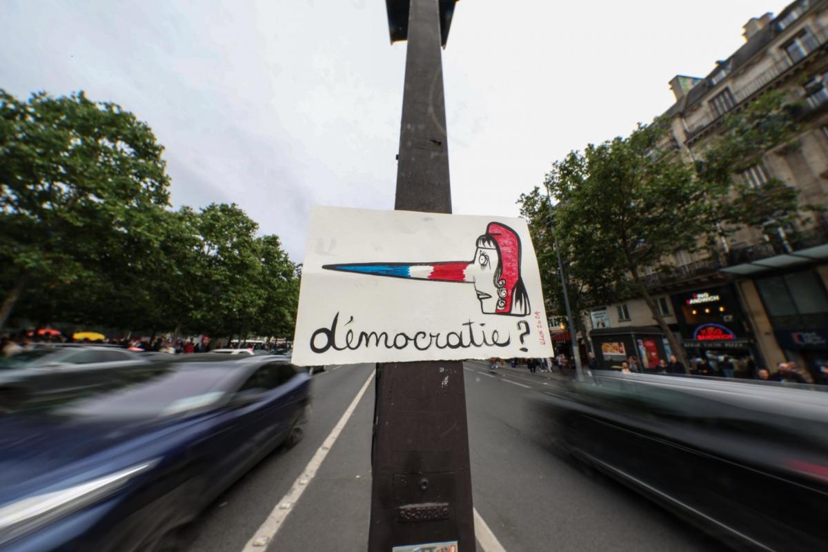 Un cartel colgado en un semáforo durante una manifestación contra la extrema derecha en París en el que se lee '¿Democracia?'