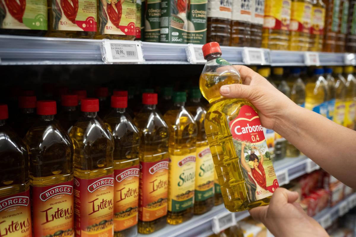 Una persona sostiene una botella de aceite de oliva en un supermercado en España.