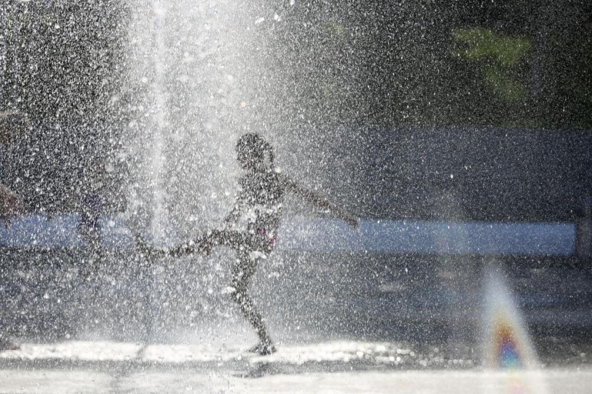 Una niña juega en una fuente