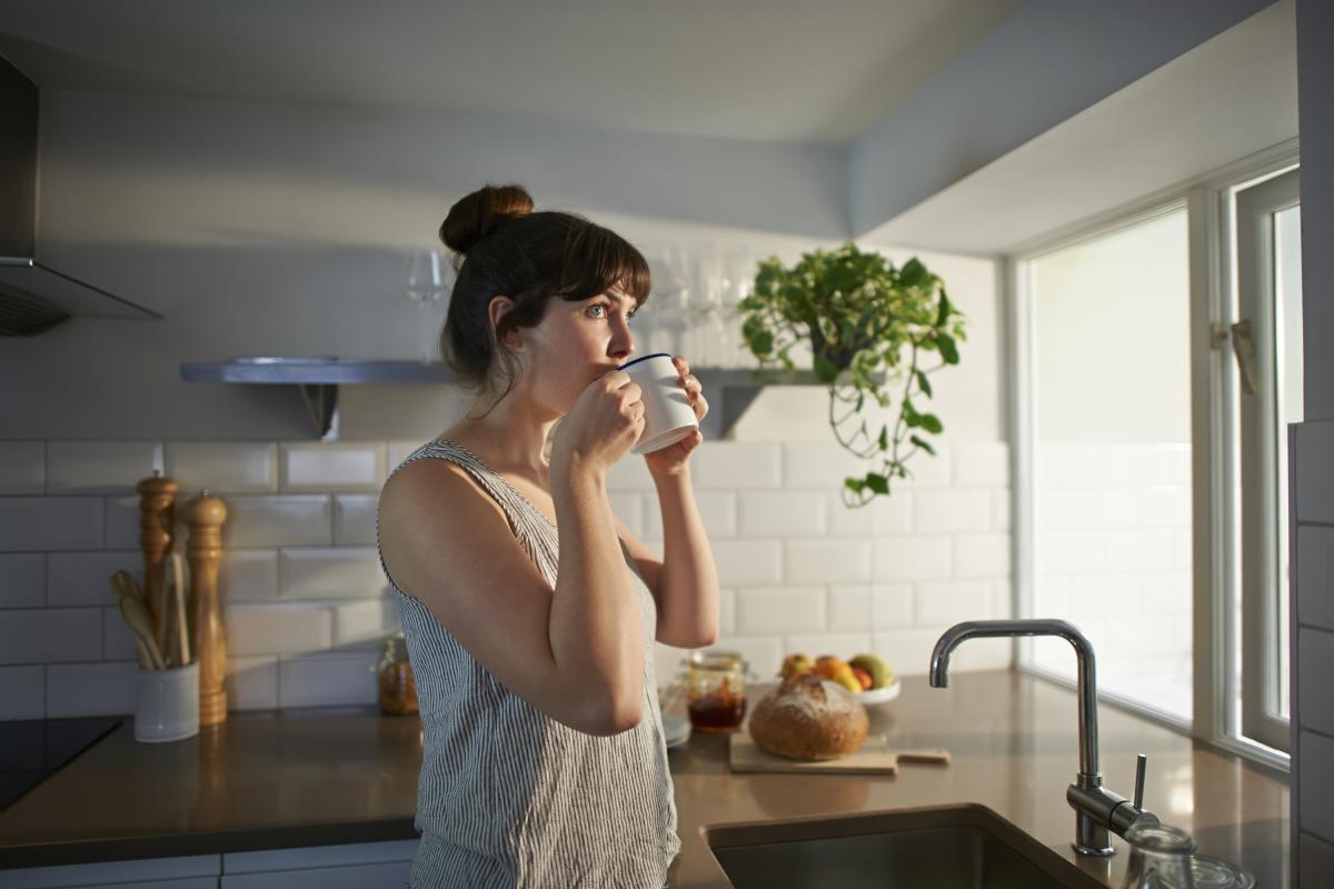 Una mujer tomando un café en su casa.