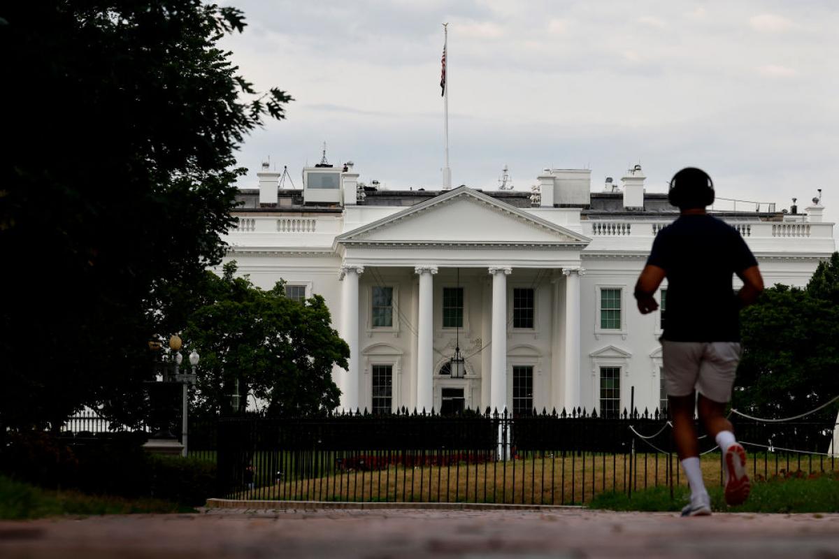 Un hombre corre por el Parque de Lafayette, en Washington DC, con la Casa Blanca al fondo.