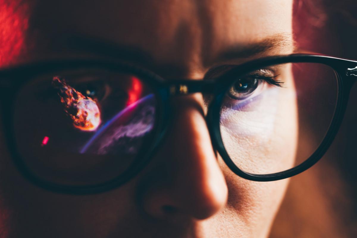 Recreación digital de un asteroide reflejado en el cristal de las gafas de una persona.