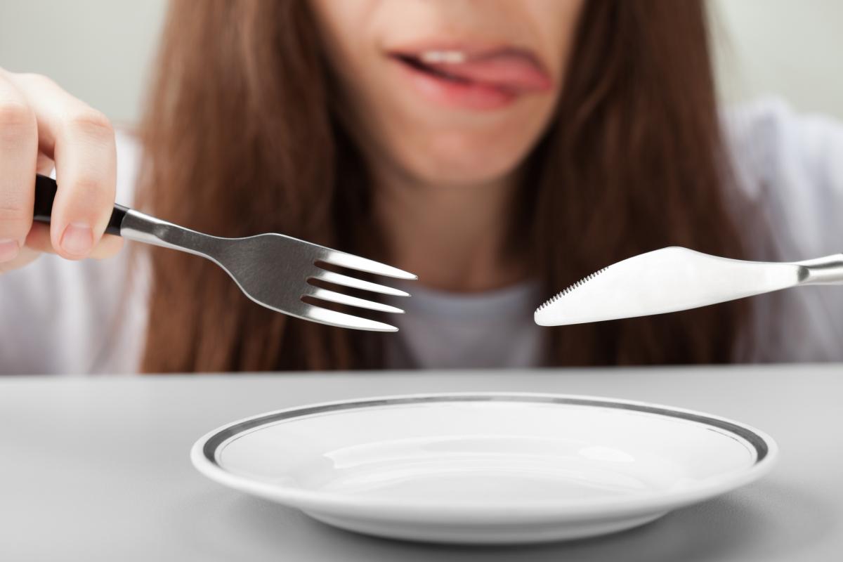 Una persona relamiéndose ante un plato.