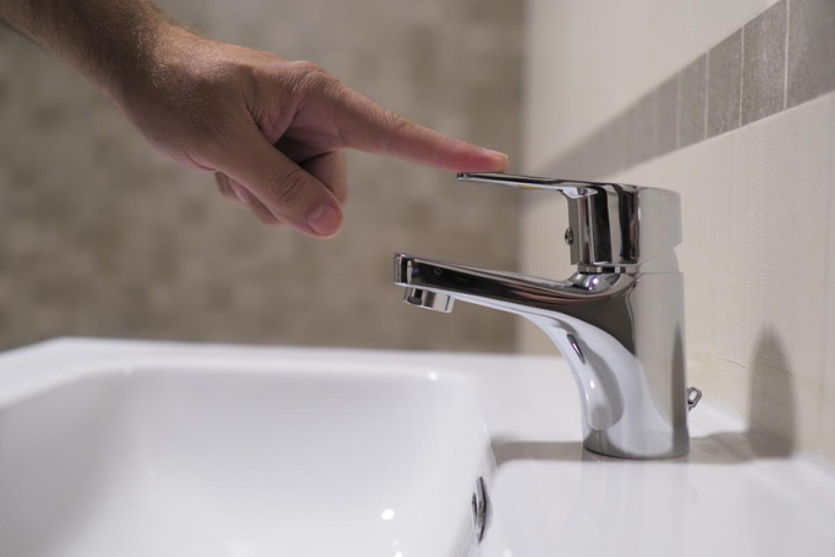Imagen de archivo de una persona cortando el agua de un grifo.
