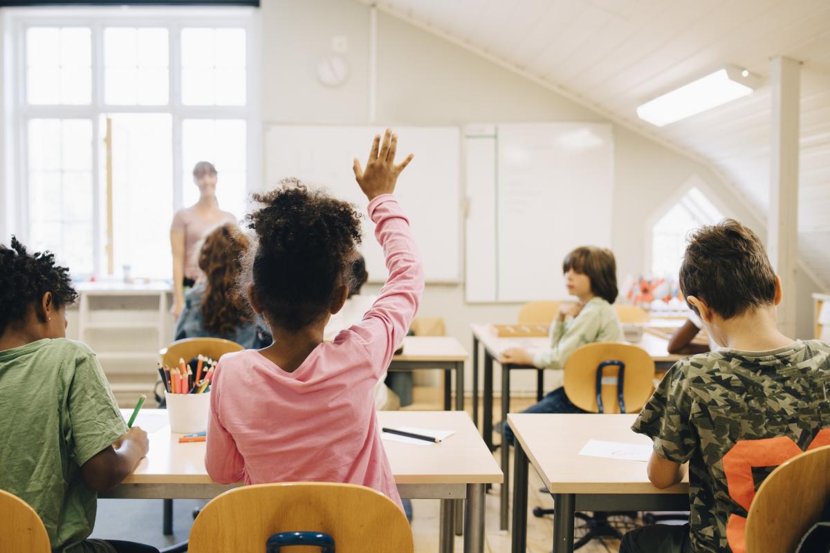 Un niña levanta la mano en clase.