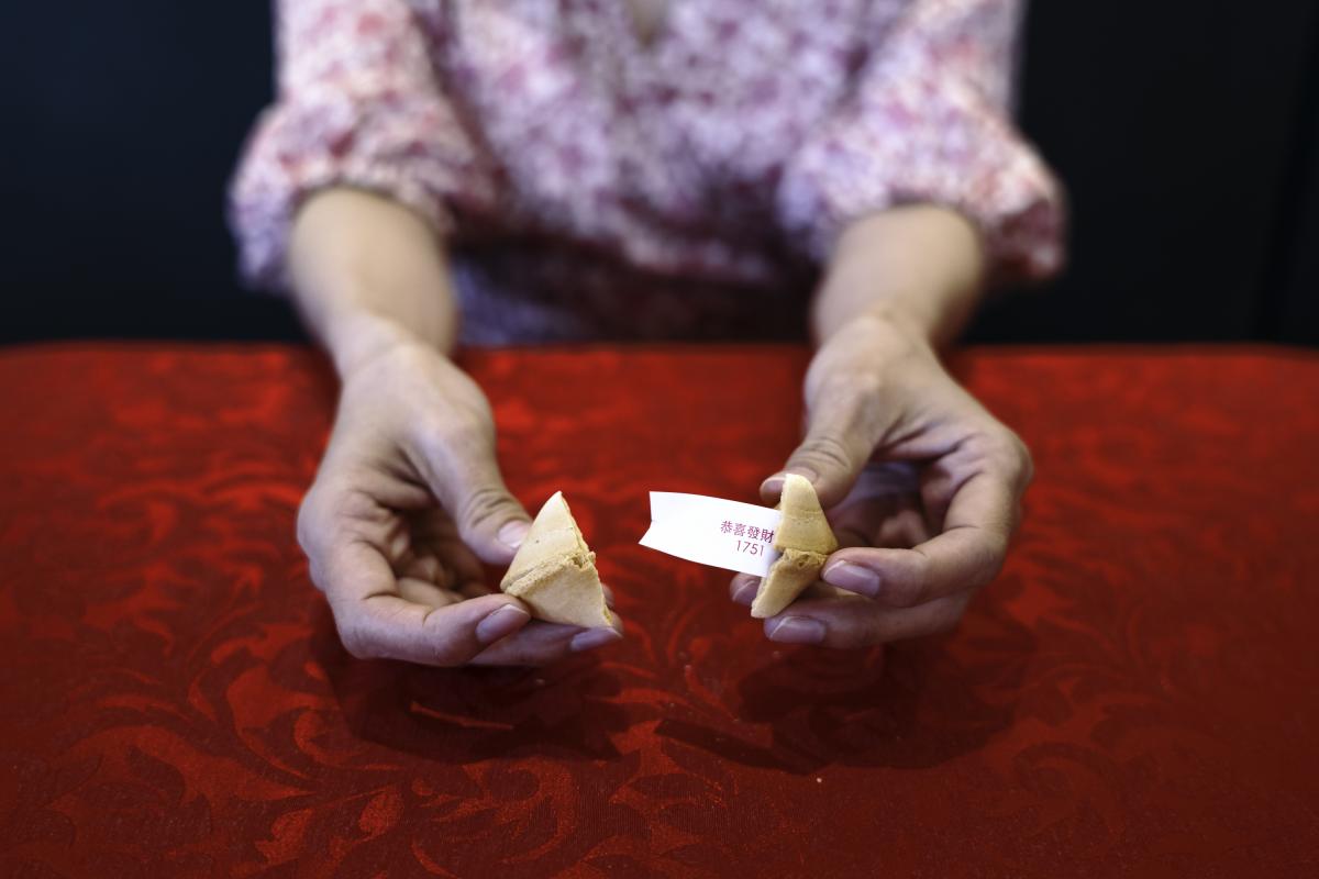 Foto de archivo de una persona abriendo una galleta de la fortuna.