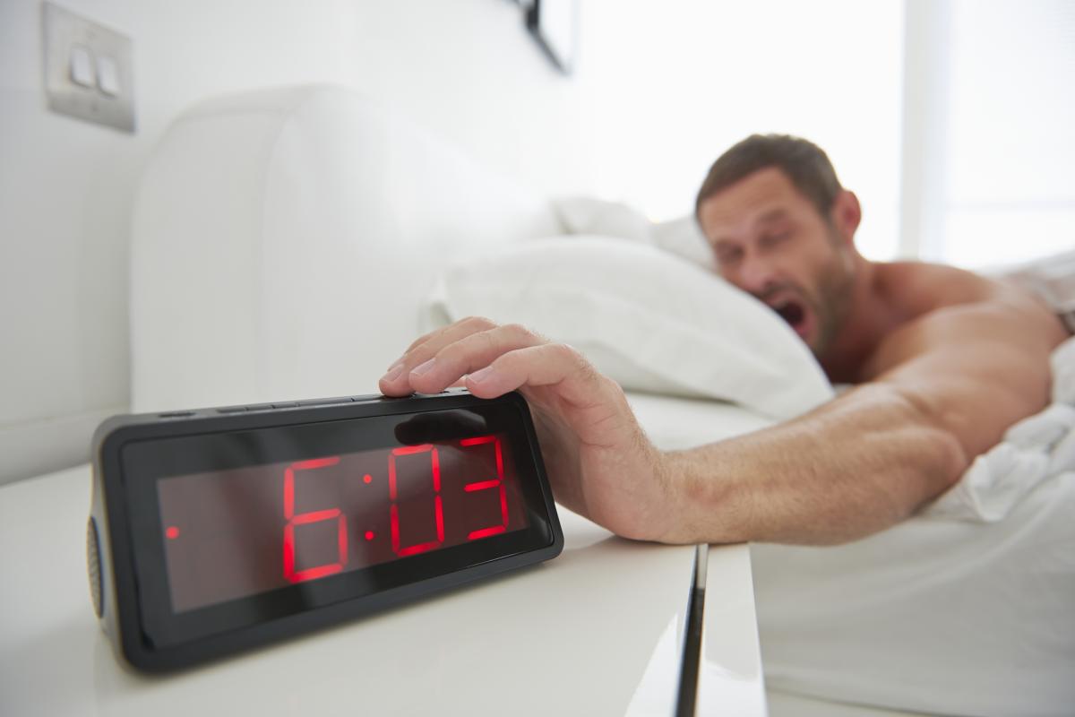 Un hombre apagando la alarma del despertador.