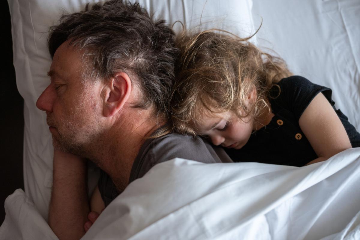 Padre e hija duermen juntos.