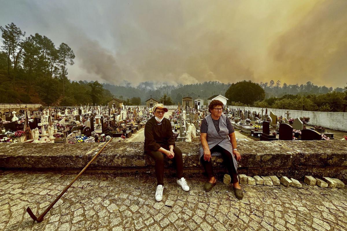 Dos mujeres, sentadas en el cementerio en Figueiredo de Alva,contemplan varias columnas de humo procedentes de uno de los incendios den Portugal.