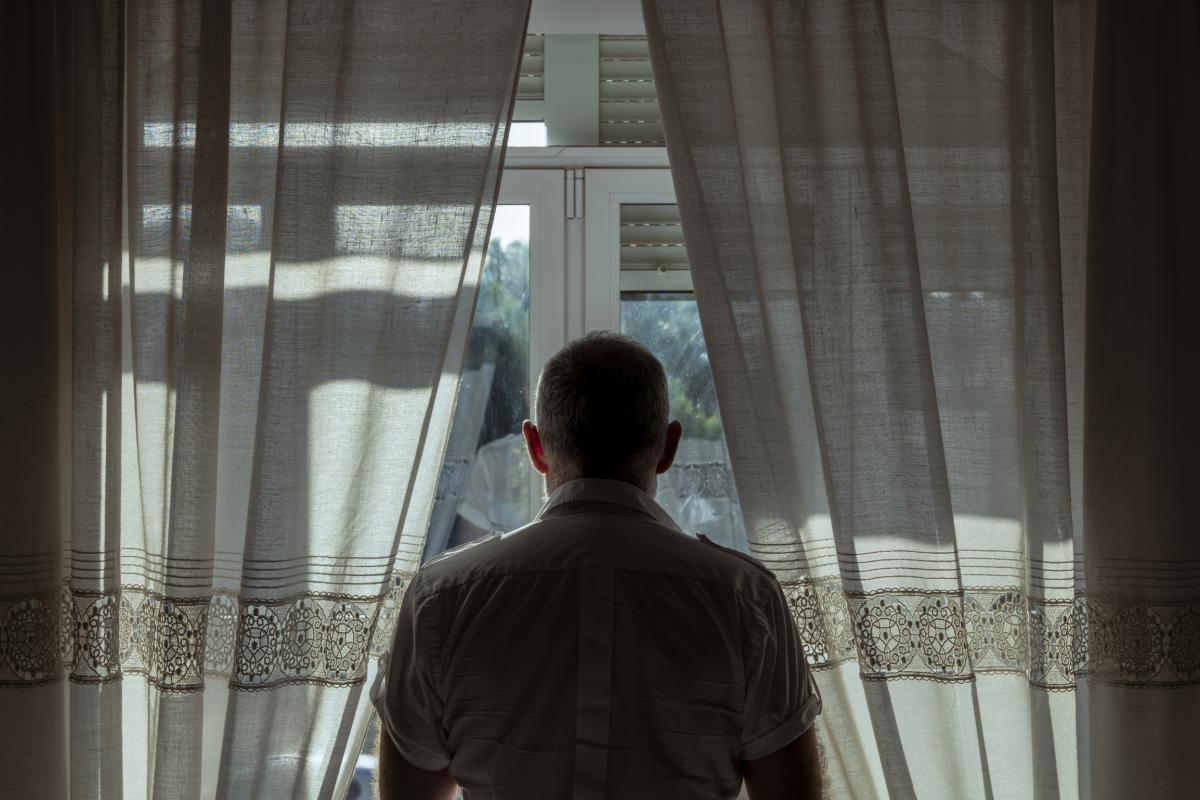 Imagen de archivo de una persona mayor viendo algo por la ventana.