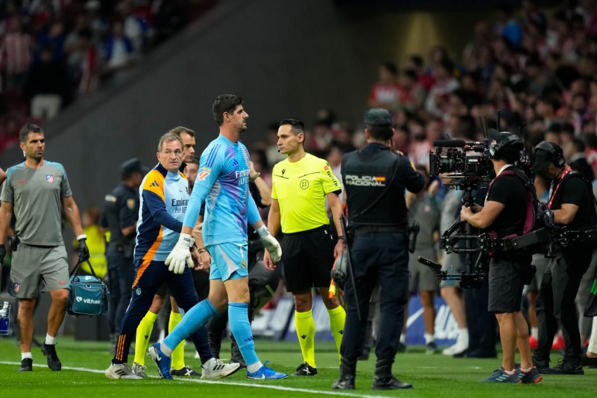 Thibaut Courtois se retira entre policías tras la suspensión temporal del partido entre Atlético y Real Madrid