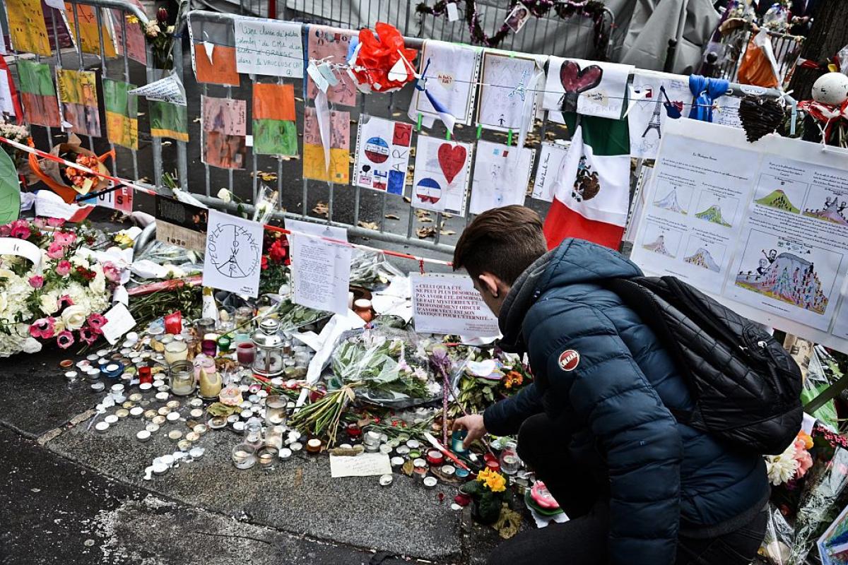 Un joven deposita flores en homenaje a los atentados de París de 2015.