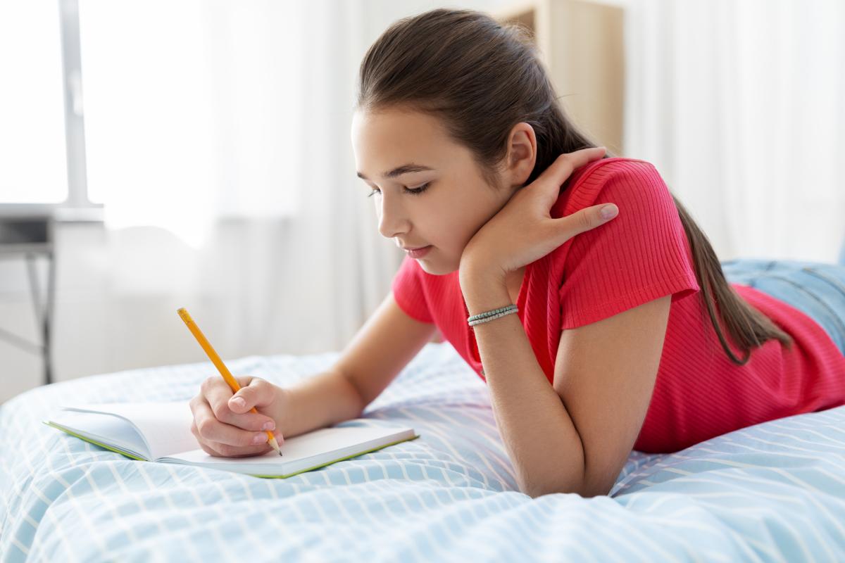 Una adolescente escribiendo en su cuaderno.