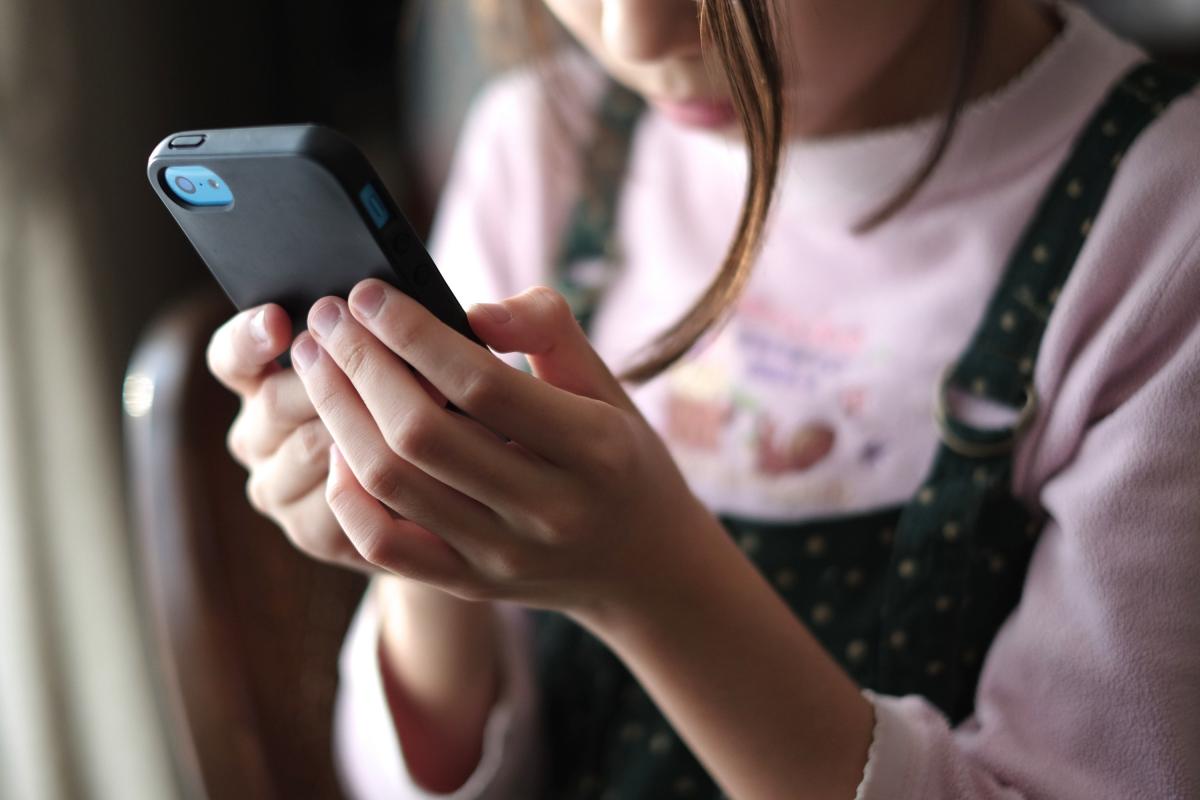 Foto de archivo de una niña con un teléfono móvil.