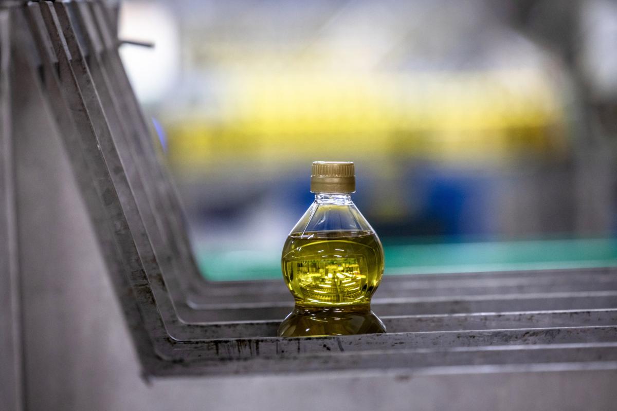 Imagen de una botella de aceite de oliva en una cinta transportadora.
