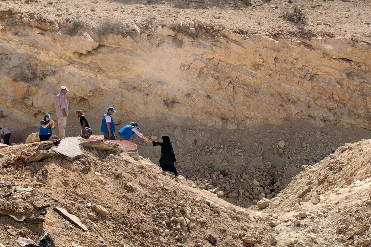 Una familia cruza el cráter dejado tras un bombardeo israelí en la frontera entre Libia y Siria.