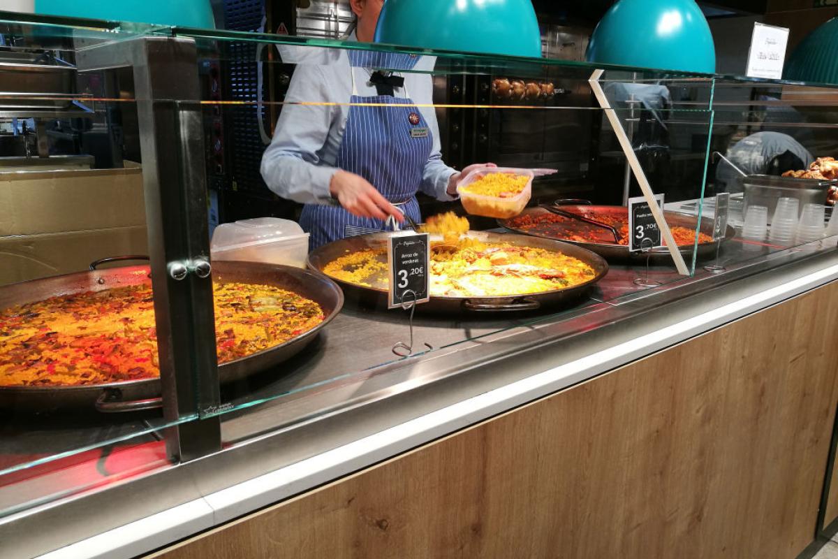 Una trabajadora de un supermercado prepara una ración de un plato preparado