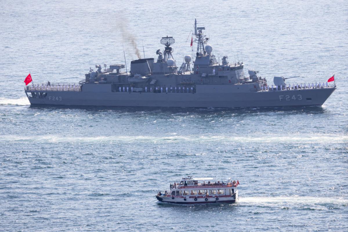 Un ferry pasa junto a uno de los buques que forman parte de la flota naval turca.