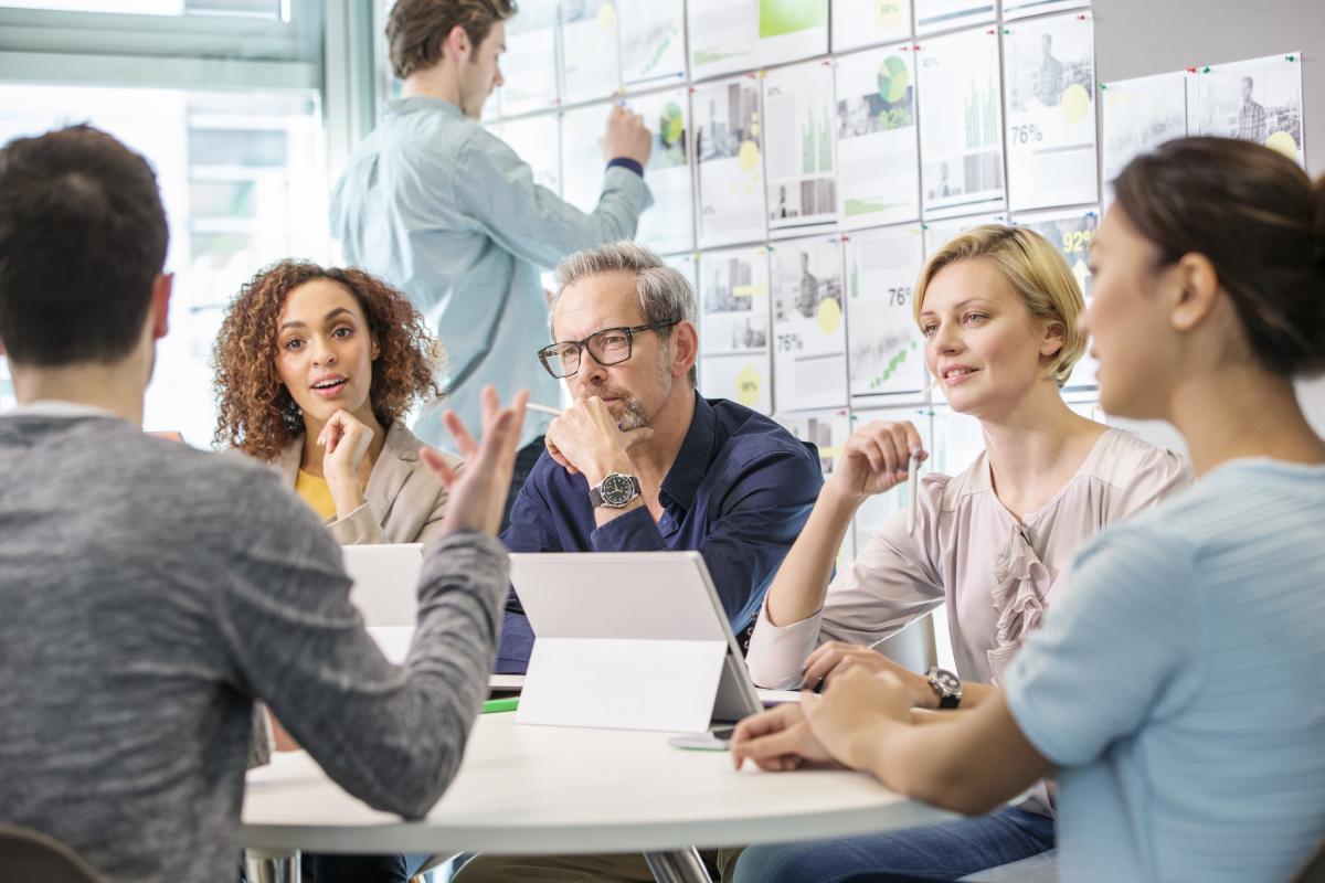 Varias personas hablando en una reunión.
