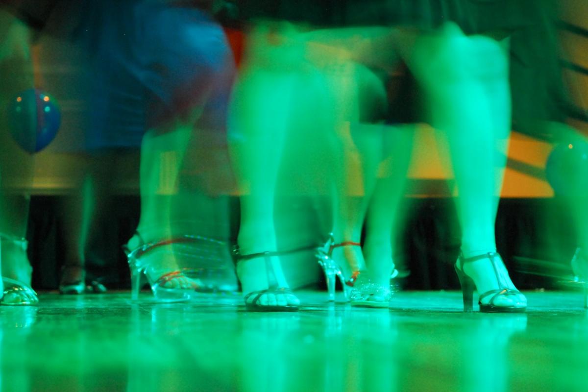 Un grupo de mujeres, de tacones, baila en la pista de un club.
