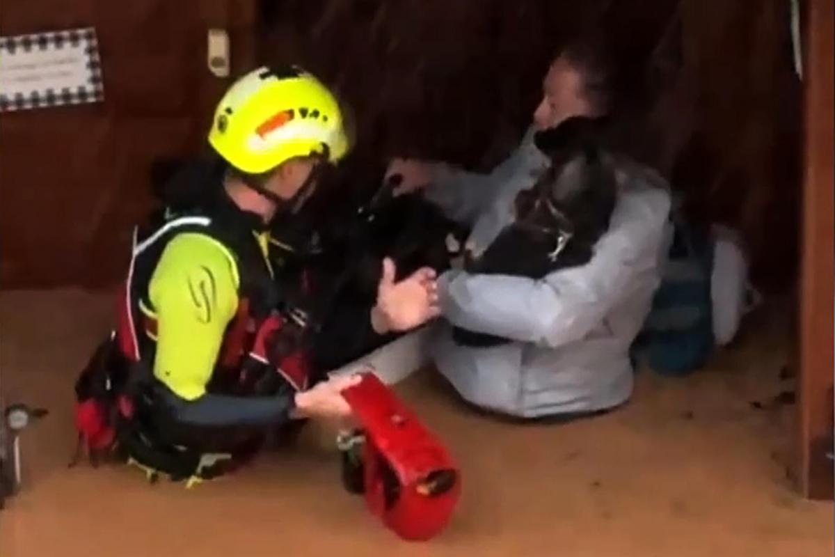 Captura de video que muestra un integrante de las fuerzas de socorro rescatando a una mujer dentro de una inundación en Valencia.