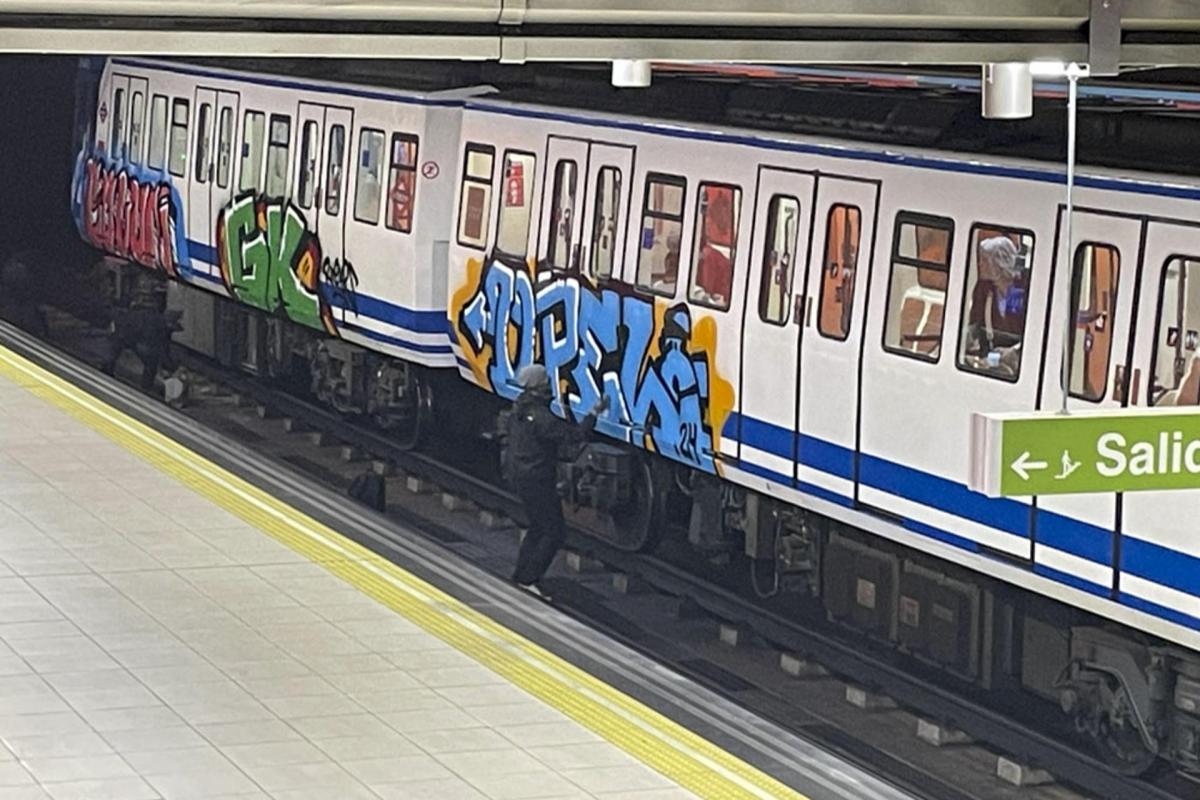 Uno de los grafiteros vandalizando el vagón del tren de la Línea 1 del Metro de Madrid.