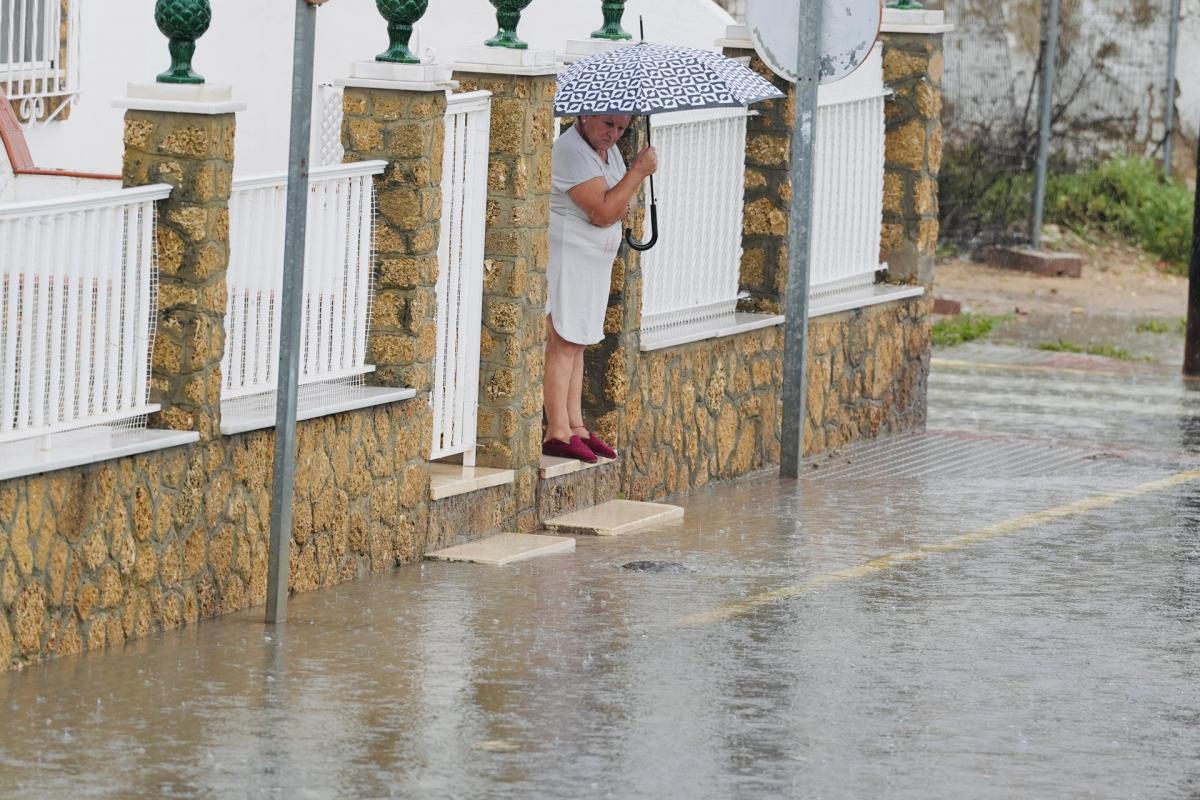 Una persona intenta cruzar una calle inundada en la barriada Bazán de San Fernando (Cádiz).