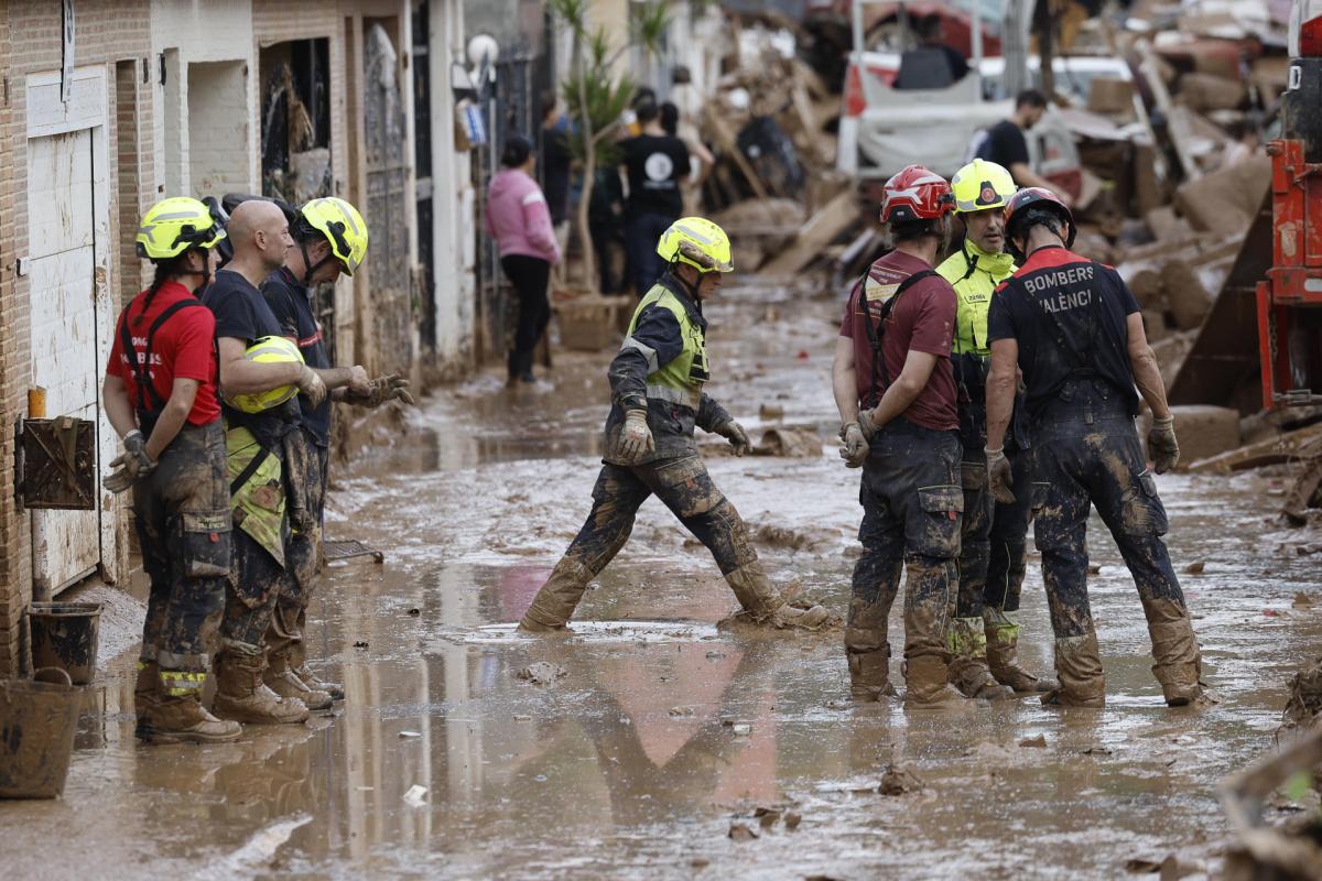 Efectivos del cuerpo de bomberos trabajan en la limpieza y retirada del lodo en Alfafar (Valencia).