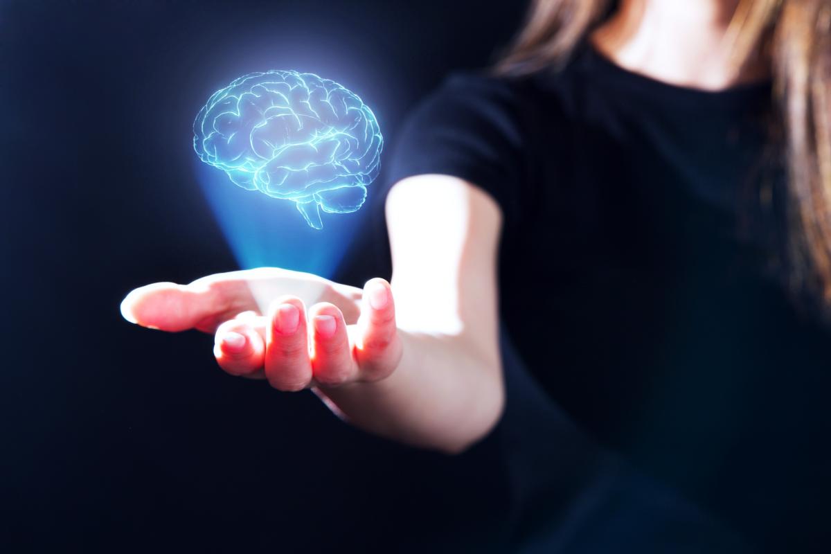 Mano de mujer que muestra un holograma del cerebro humano.